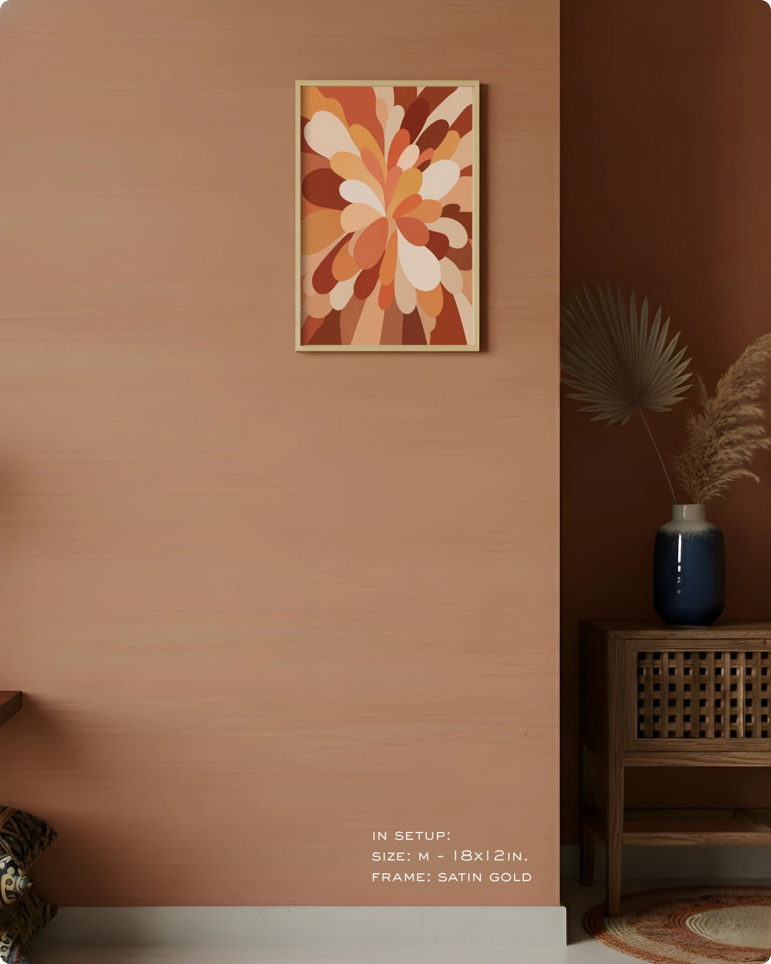 A framed abstract floral wall art print hangs on a warm terracotta-colored wall in a styled interior setting. The artwork features layered petal-like shapes in orange, brown, cream, and rust tones.