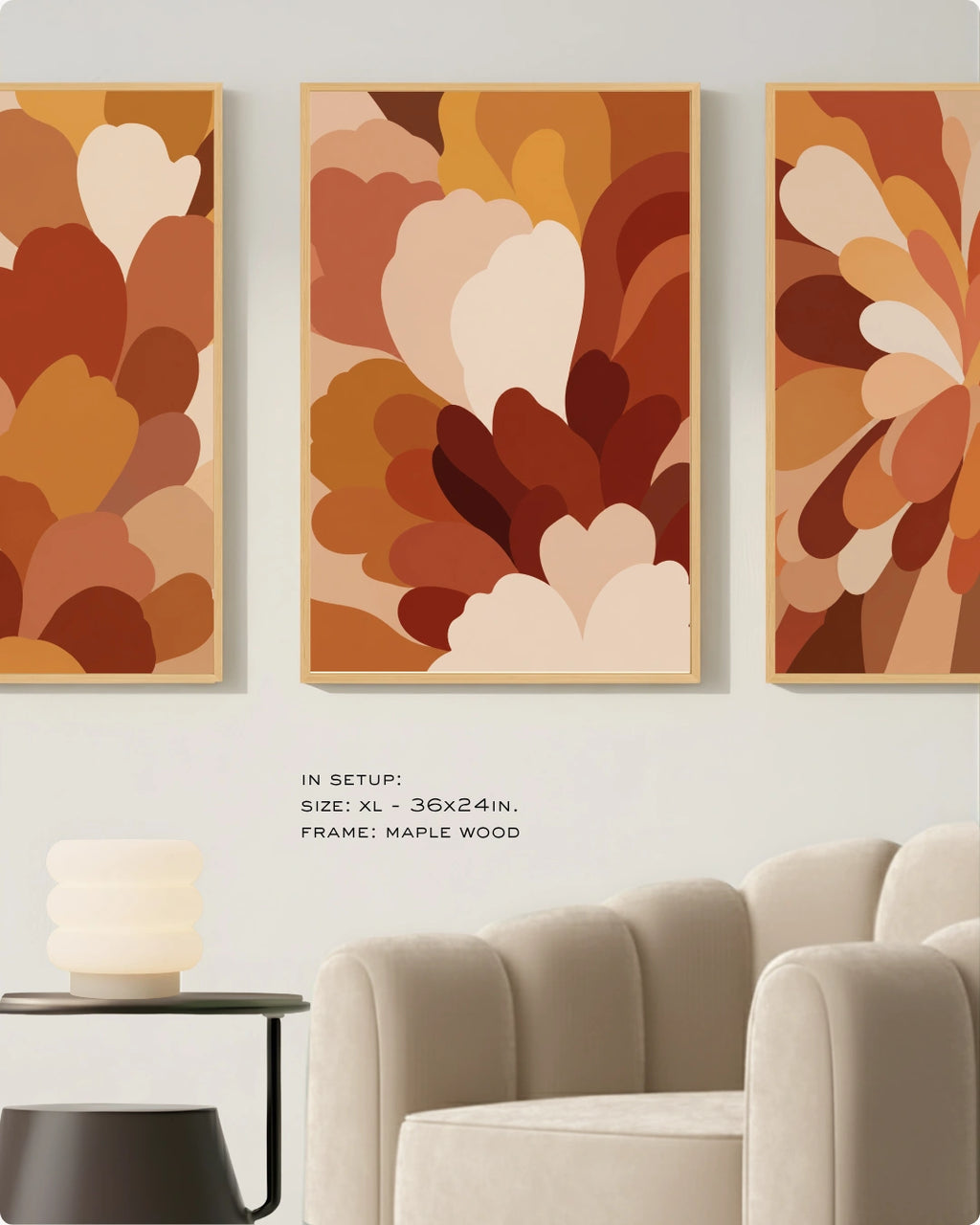 Three framed abstract wall art prints in warm autumn tones hang above a cream sofa in a styled interior. The artwork features layered organic shapes in orange, rust, brown, tan, and cream.