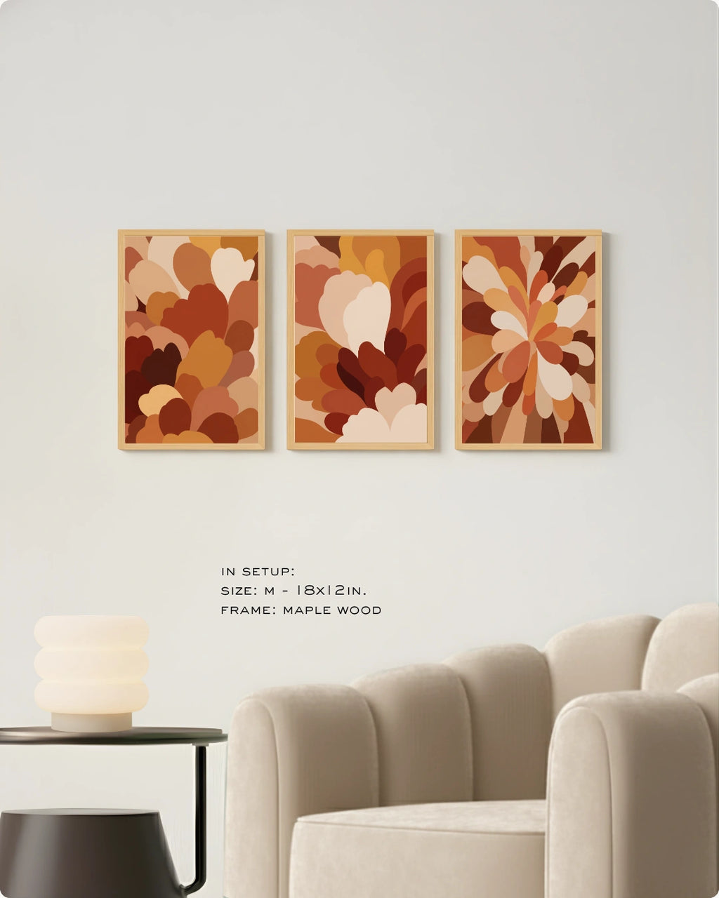 Three framed abstract floral art prints in warm earthy tones displayed on a white wall above a beige armchair, with small text noting size and maple wood frame.