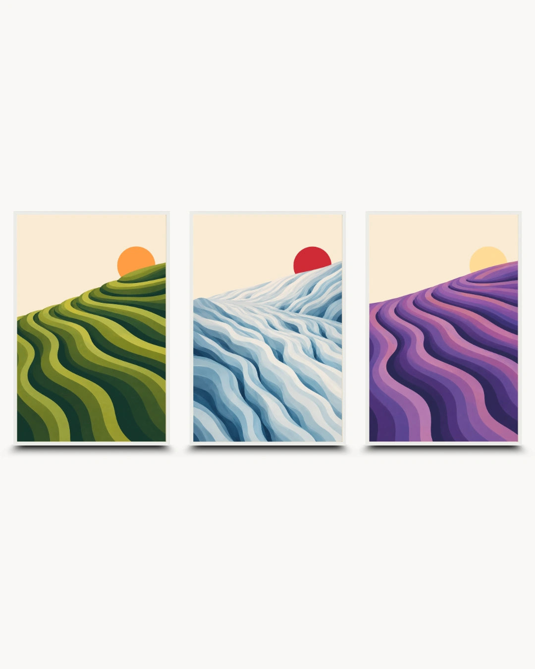 A three-panel framed wall art set featuring stylized landscape scenes: green rolling hills with an orange sun, blue and white wavy hills with a red sun, and purple lavender-like hills with a yellow sun, shown on a light gray background.