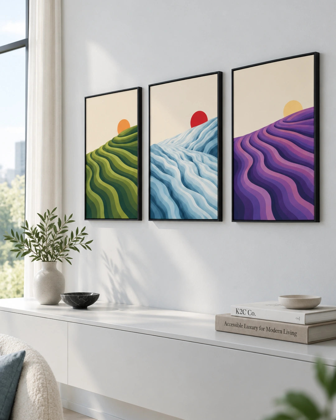 Lifestyle mockup of the 3 piece canvas art landscape in black frames styled above a sleek white media console in a bright room.