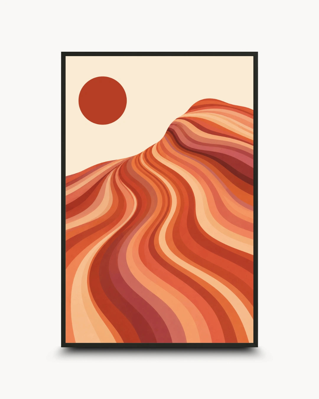 A framed art print featuring a retro-style desert landscape with wavy orange and red sand dunes under a solid red sun on a cream background, displayed on a light gray wall.