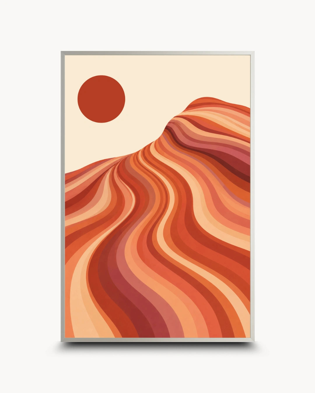 A framed art print featuring a minimalist desert landscape with wavy orange and red dunes under a solid red sun on a cream background, shown against a light gray backdrop.