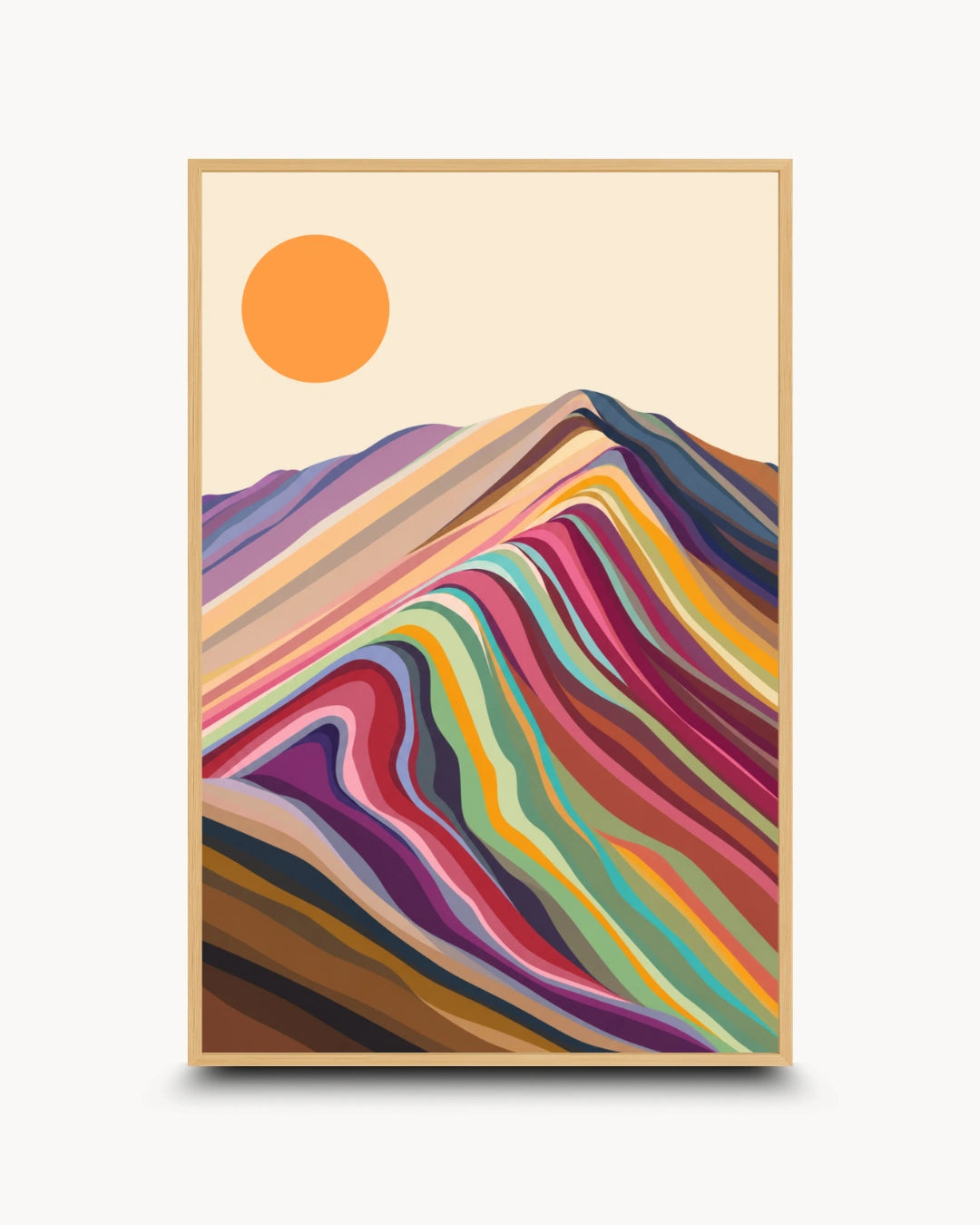 A framed art print featuring a stylized mountain landscape with layered multicolored hills and a simple orange sun on a cream background, shown against a light gray wall.