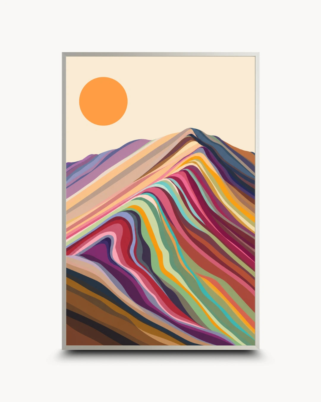A framed art print featuring a stylized mountain landscape with layered multicolored hills and a simple orange sun on a cream background, shown against a light gray wall.