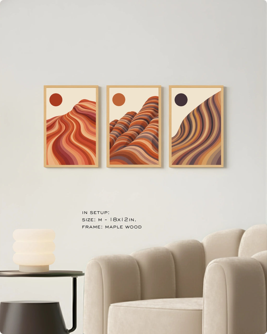 Three framed abstract landscape wall art prints hang above a cream sofa in a modern living room. Each print shows a warm-toned wavy desert or mountain scene in orange, brown, and beige, with small sun-like circles.