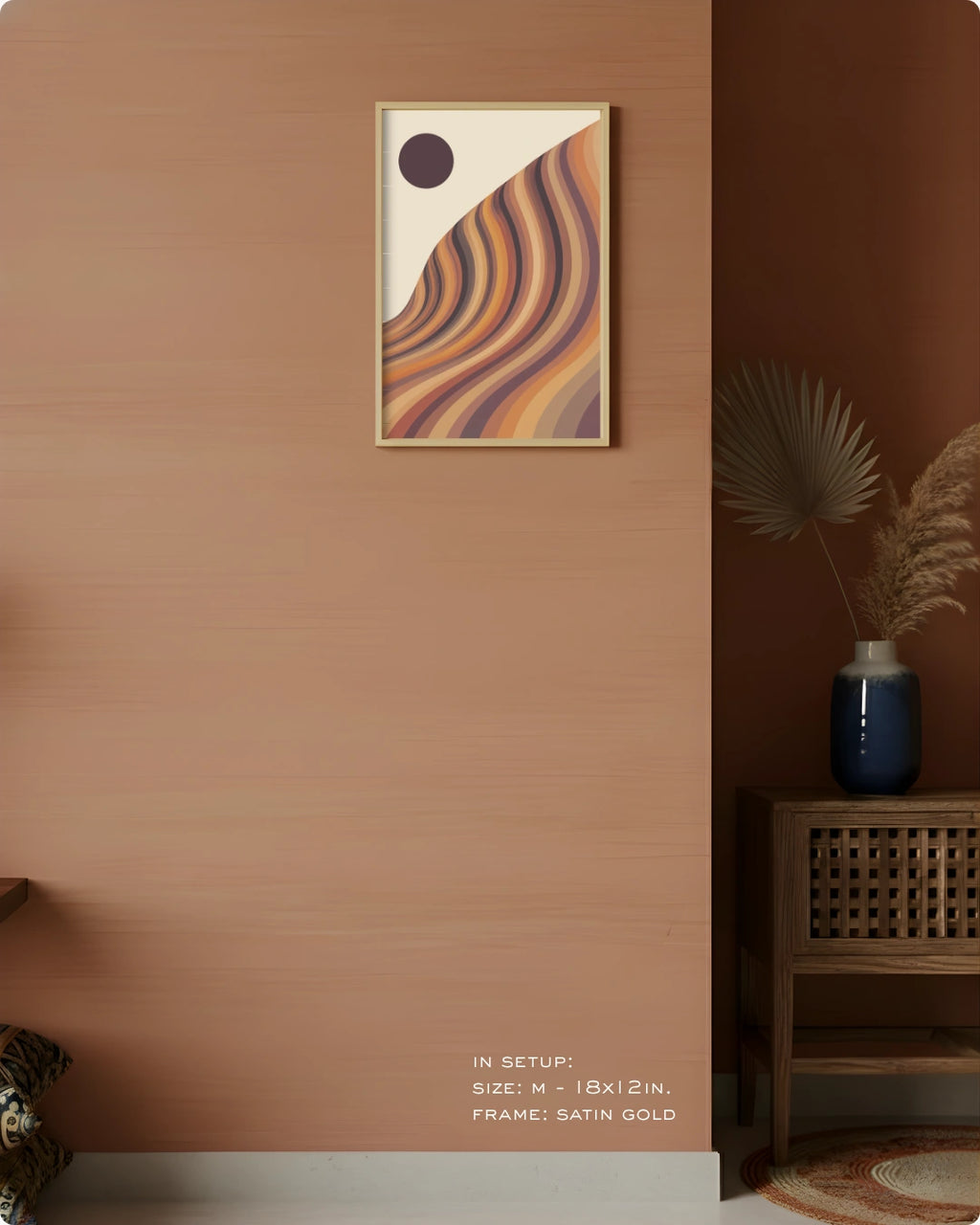 A framed abstract wall art print hangs on a warm terracotta-colored wall in a styled interior. The artwork features flowing wavy stripes in tan, orange, brown, and purple with a dark oval near the top.