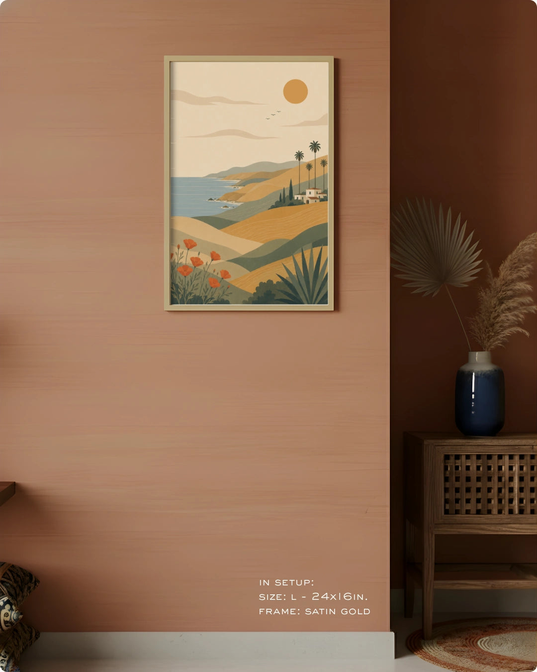 A framed vertical art print featuring a retro coastal landscape with hills, palm trees, a blue sea, and a sun, displayed on a warm terracotta wall in a styled interior setting.