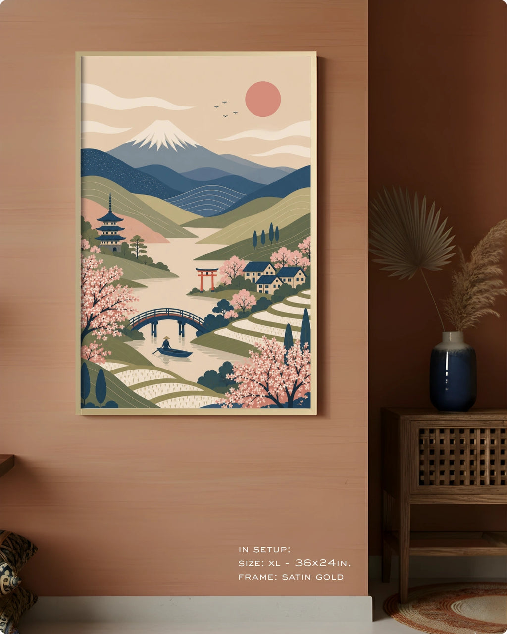 A framed art print featuring a stylized Japanese landscape with mountains, cherry blossoms, a bridge, and a pagoda, displayed on a warm brown wall in a styled interior setting.