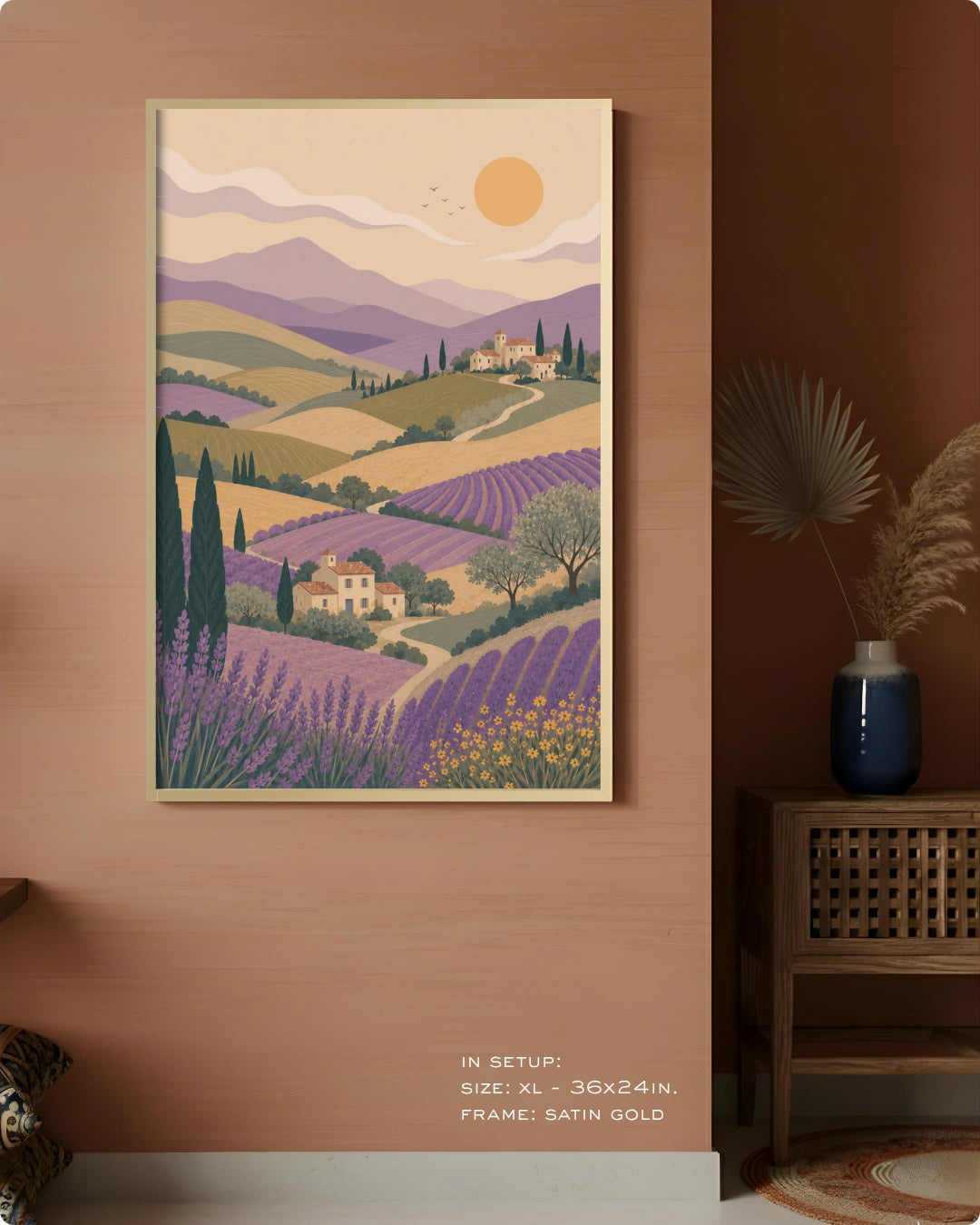 A framed art print depicting a stylized Provence landscape with lavender fields, hills, mountains, and a sun, displayed on a warm terracotta wall in a styled interior setting.