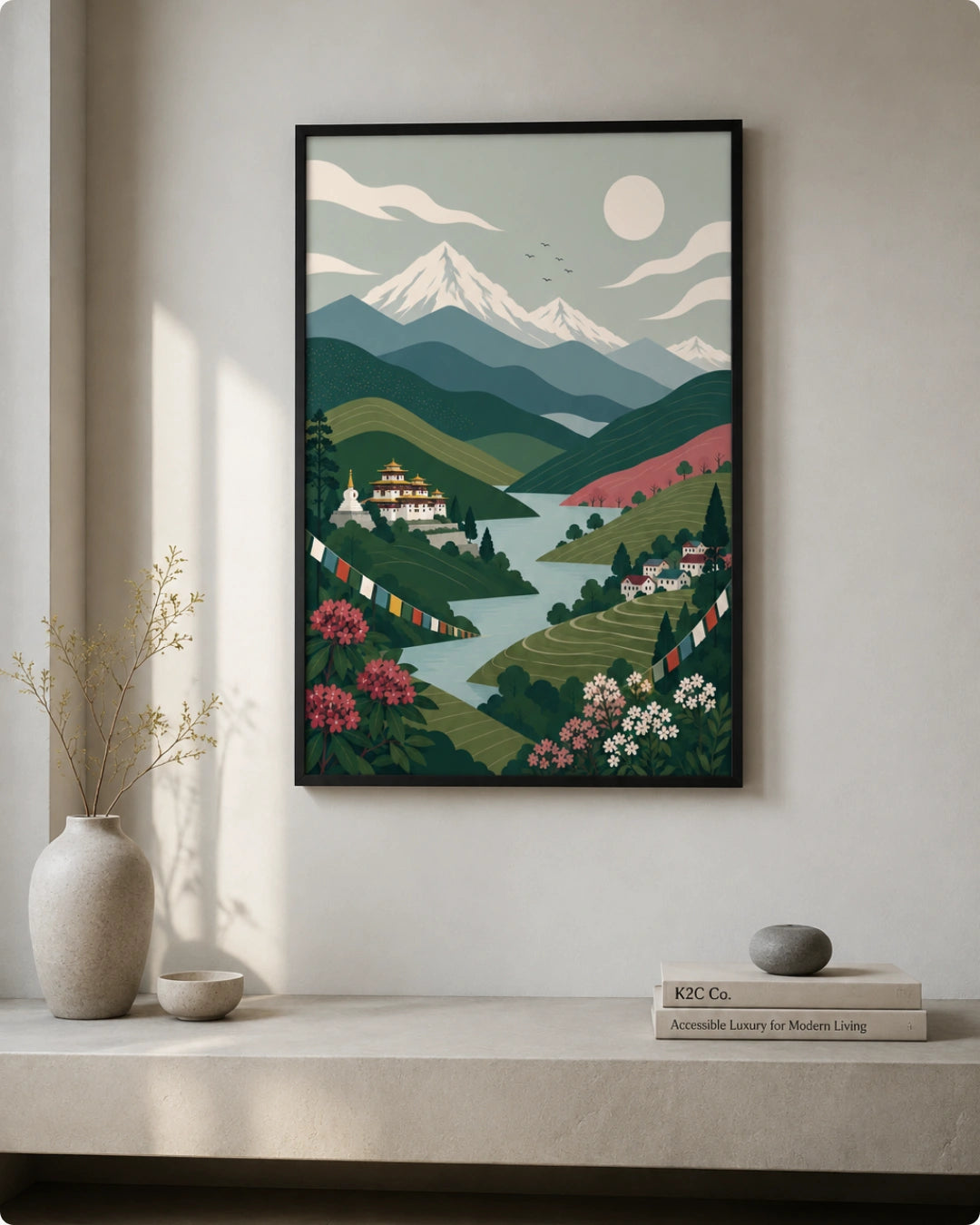 A framed art print depicting a stylized mountain landscape with green hills, a river, flowers, and a snow-capped peak, displayed on a wall above a shelf with decorative vases and books.