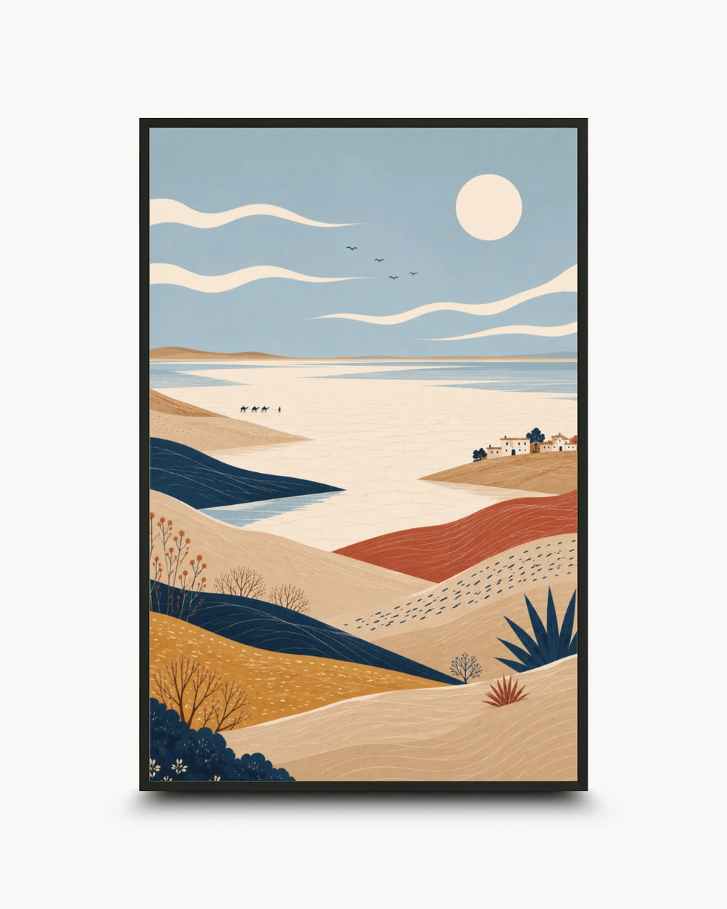 A framed landscape art print featuring a stylized desert and coastal scene with rolling beige and ochre hills, deep blue water, a pale sun, and a few small buildings, shown against a light gray background.