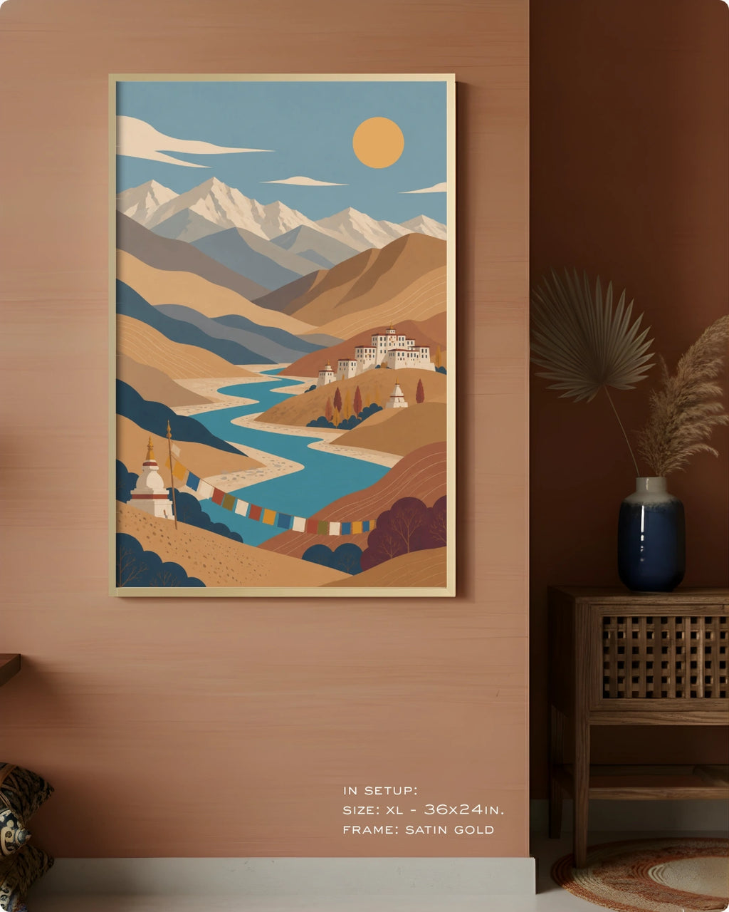 A framed art print depicting a stylized mountain landscape with a river and temples, displayed on a warm terracotta wall in a styled interior setting.