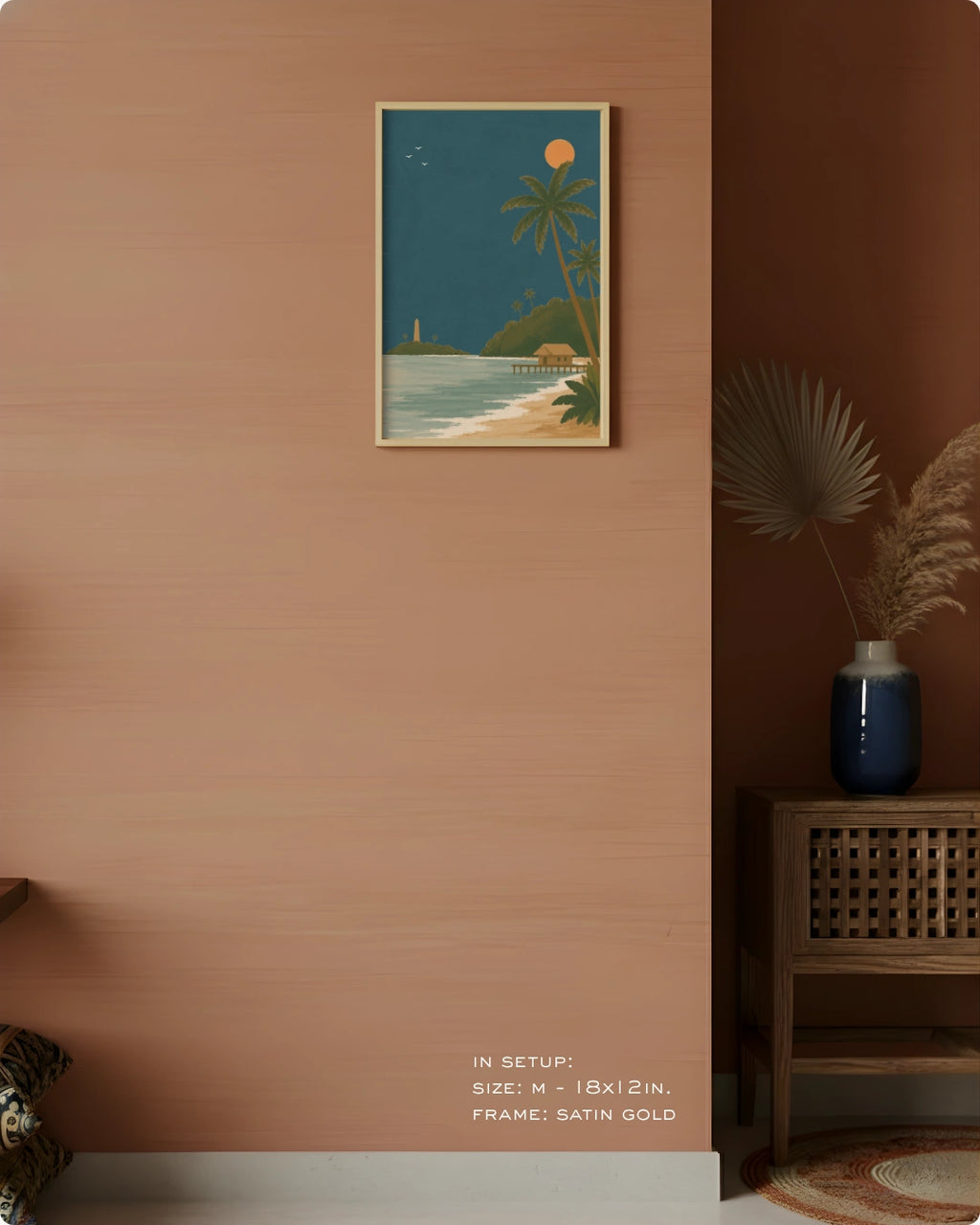 A framed vertical art print depicting a tropical beach scene with palm trees, a lighthouse, and a sunset, mounted on a warm terracotta wall in a styled interior setting.