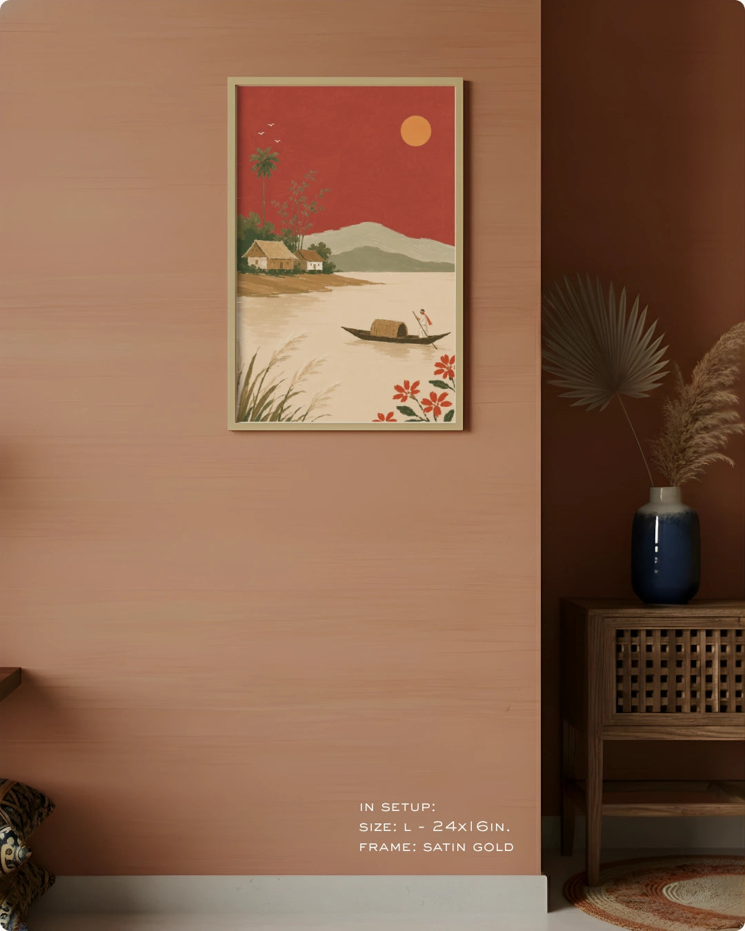 A framed art print featuring a retro-style landscape with a red sky, yellow sun, and a small boat on the water, displayed on a warm terracotta wall in a styled interior setting.
