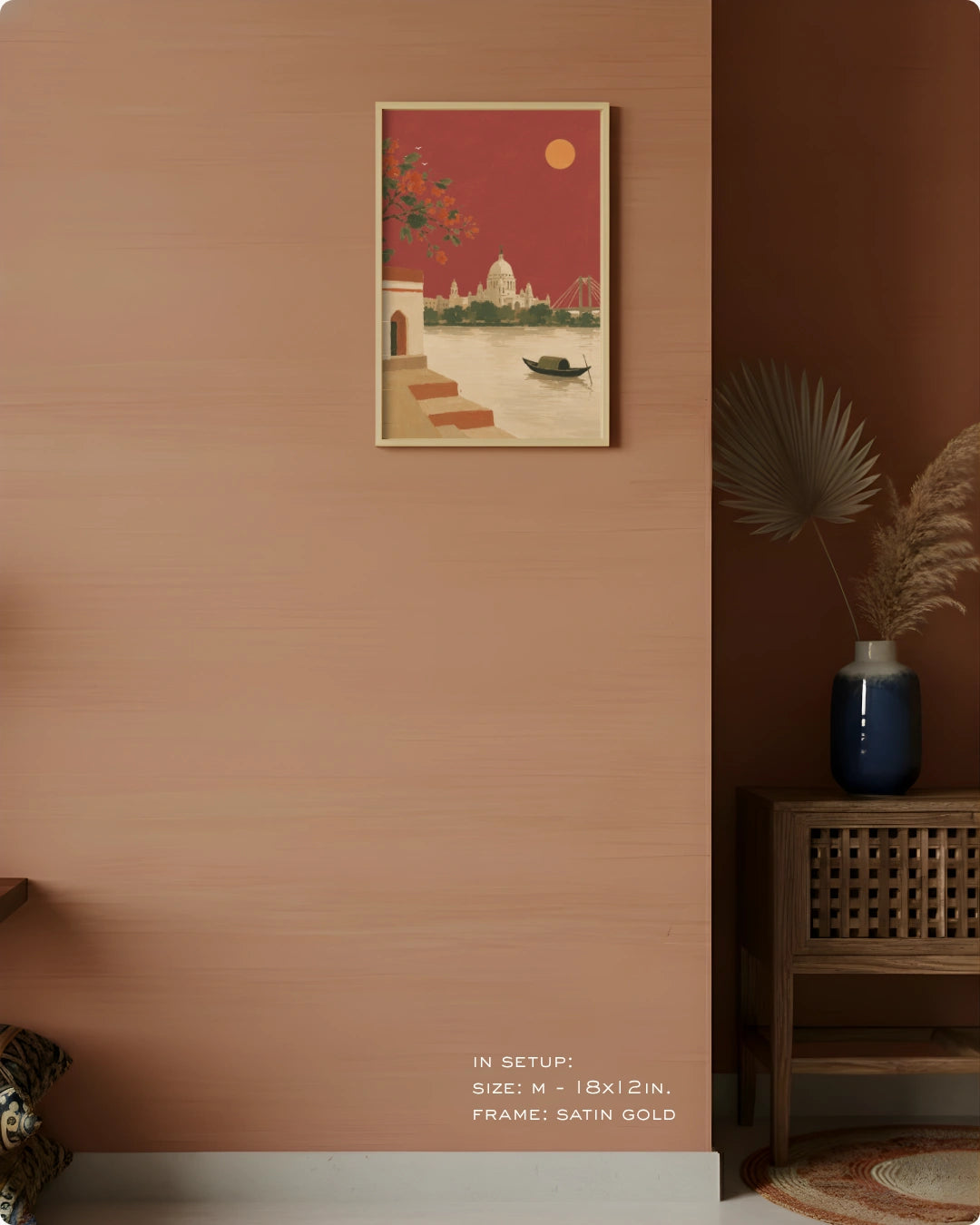 A framed art print depicting a Venetian canal scene with a gondola, displayed on a textured terracotta wall in a styled interior setting next to a wooden cabinet and a blue vase.