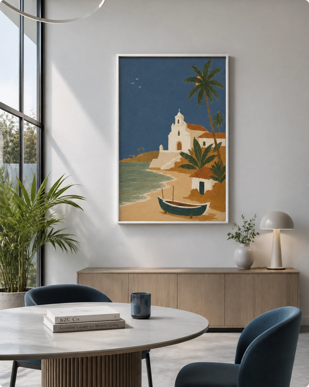A framed travel-style art print of a coastal Mediterranean scene with palm trees, a white building, blue water, and a small boat, displayed on a light gray wall in a modern dining room setting.