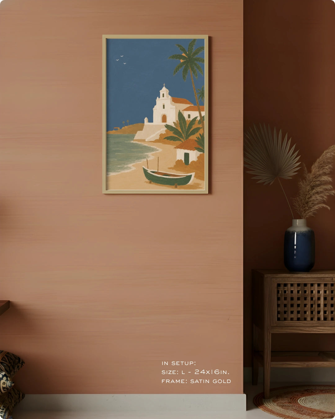 A framed art print depicting a coastal Mediterranean scene with a white church, palm trees, and a small boat, displayed on a terracotta-colored wall in a styled interior setting.
