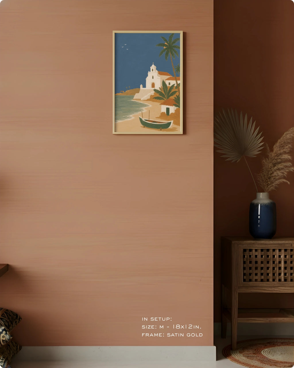 A framed art print depicting a Mediterranean coastal scene with a white church, palm trees, and a small boat, displayed on a terracotta-colored wall in a styled interior setting.
