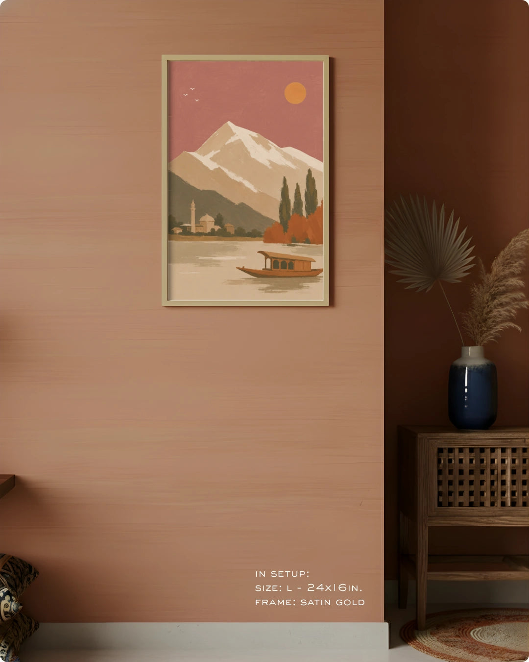 A framed art print featuring a retro-style mountain lake scene with a boat and sun, displayed on a warm terracotta wall in a styled interior setting.