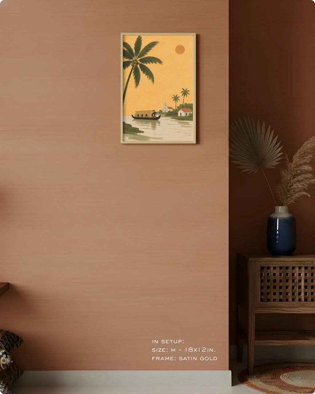 A framed vertical art print depicting a tropical beach scene with palm trees, a boat, and a small house, displayed on a warm terracotta wall in a styled interior setting.