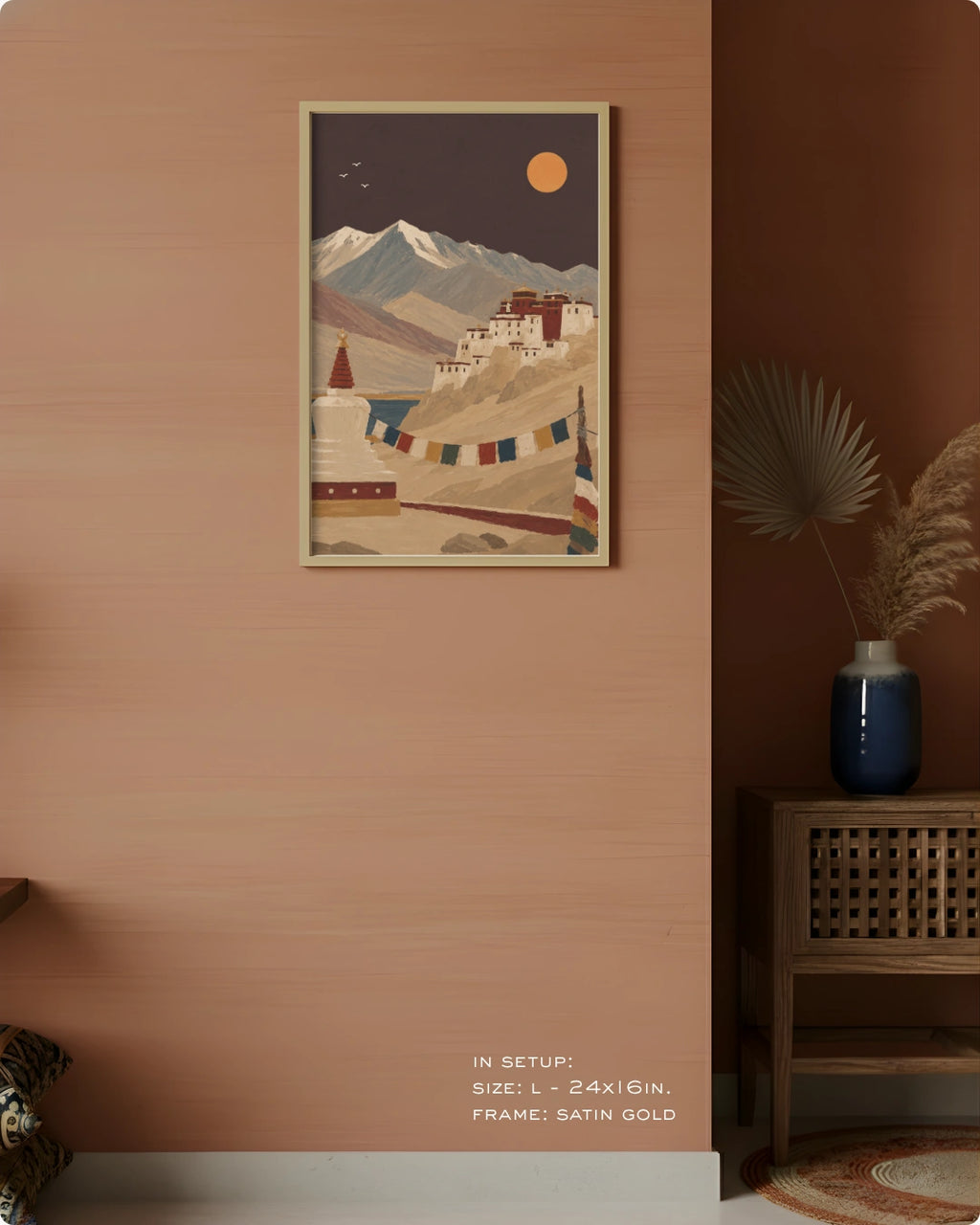 A framed art print depicting a scenic mountain landscape with a stupa and prayer flags, styled on a terracotta-colored wall in a modern interior setting.