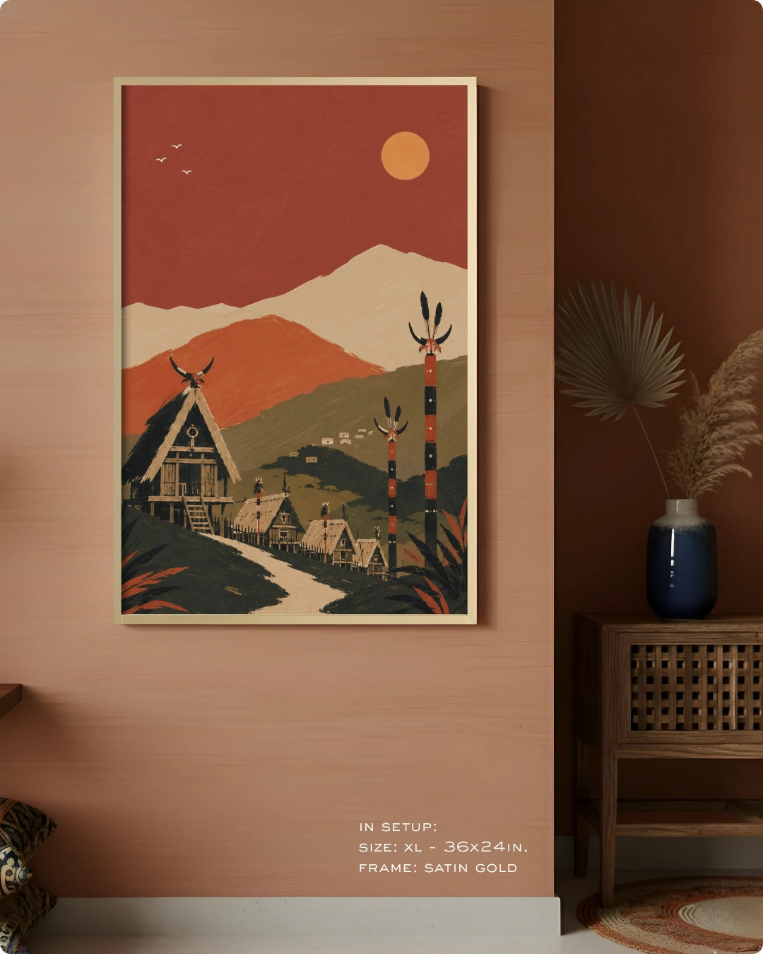 A framed art print featuring a stylized retro landscape with mountains, a village, and a sun, displayed on a warm terracotta wall in a styled interior setting.