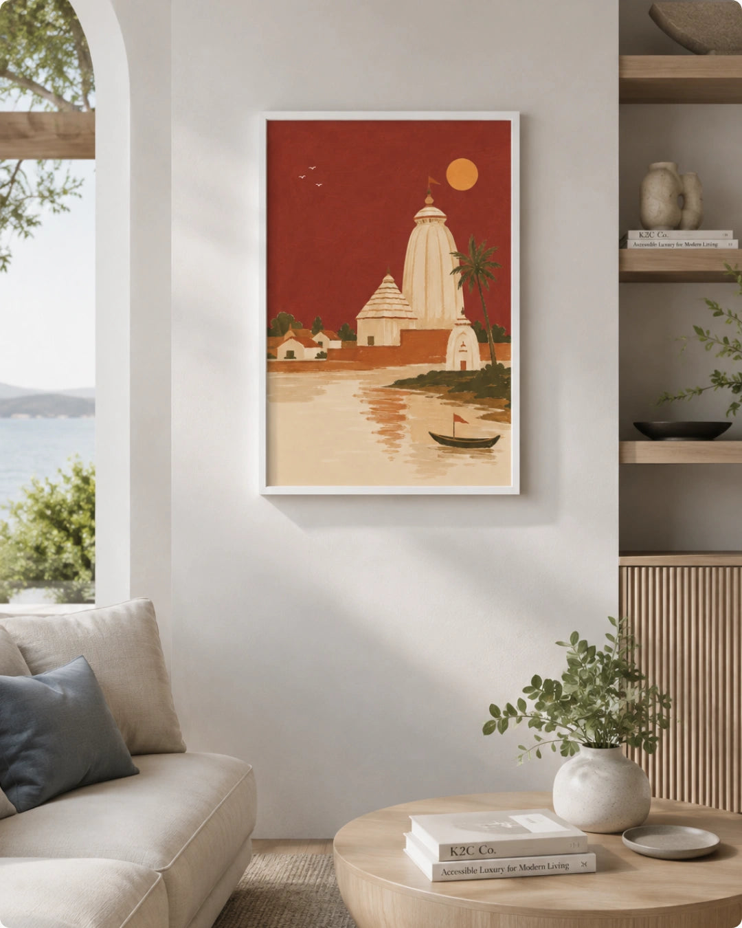 A framed art print featuring a stylized illustration of a temple by a river under a red sky, displayed on a light gray wall in a modern living room setting.