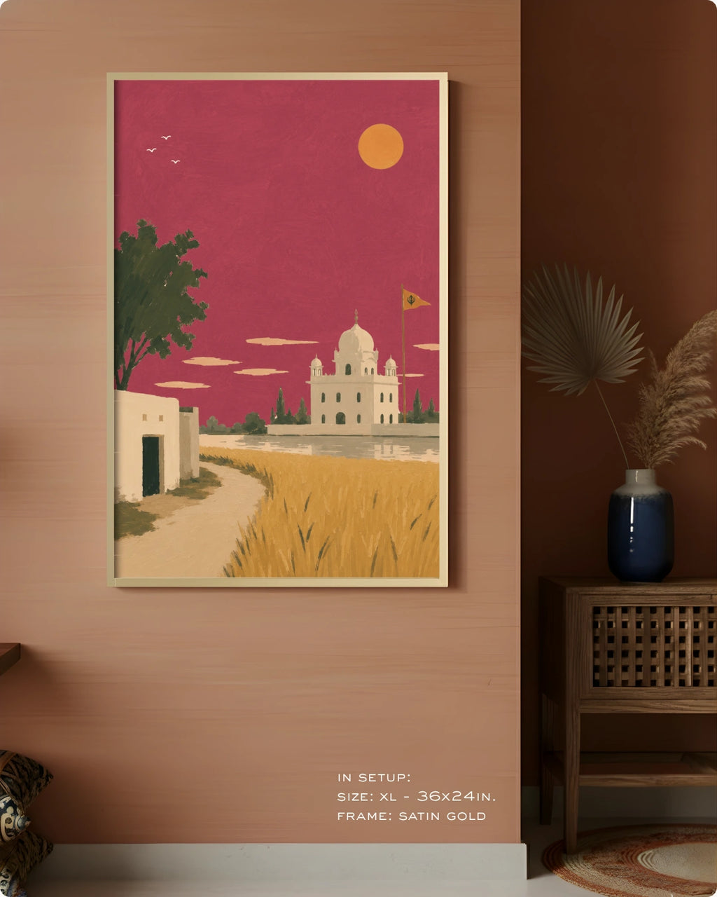 A framed art print depicting a stylized Indian landscape with a white domed temple under a magenta sky, hung on a warm brown wall in a styled interior setting.