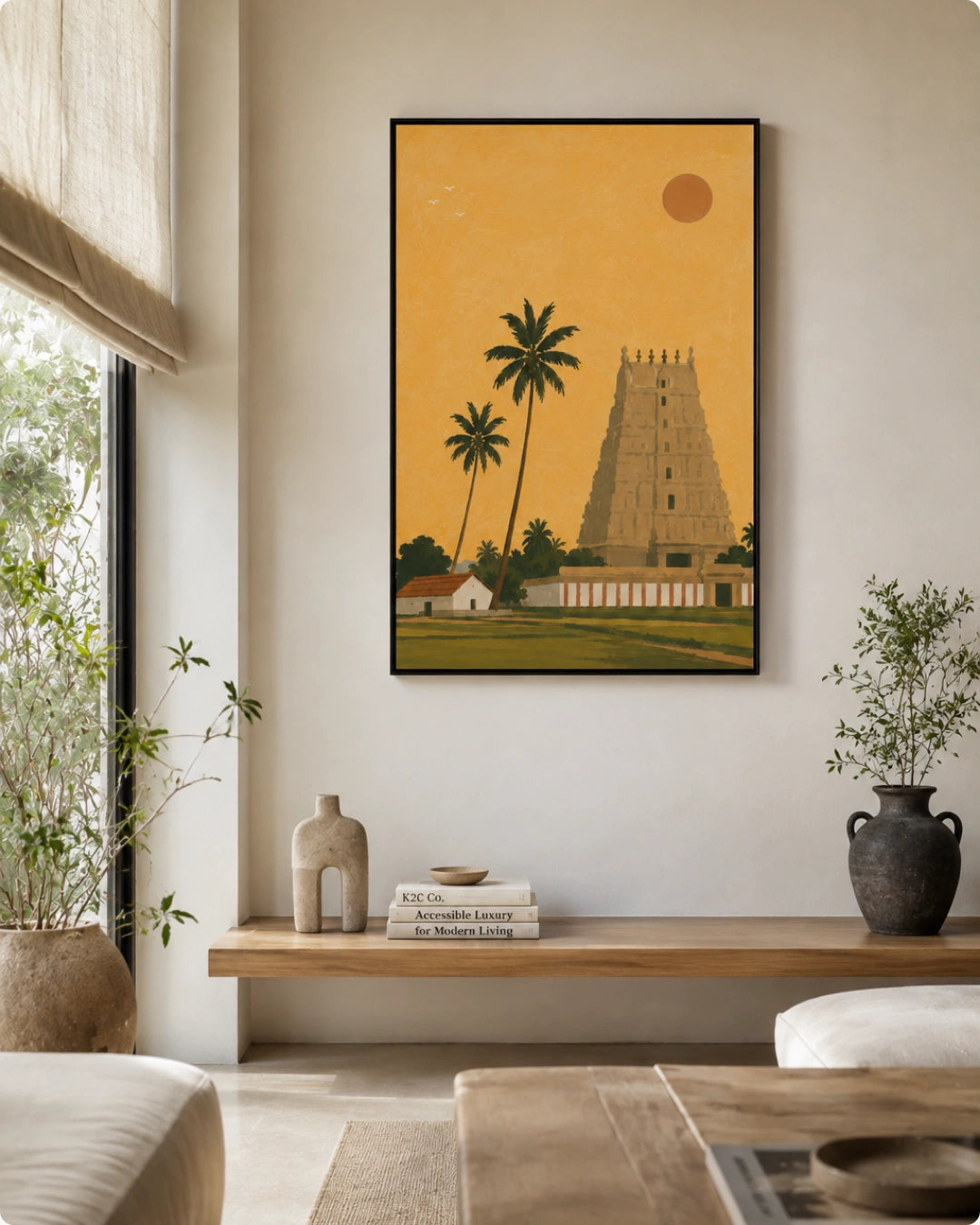 A framed art print depicting a South Indian temple tower and palm trees under a golden sky, styled on a neutral wall in a modern living room setting.