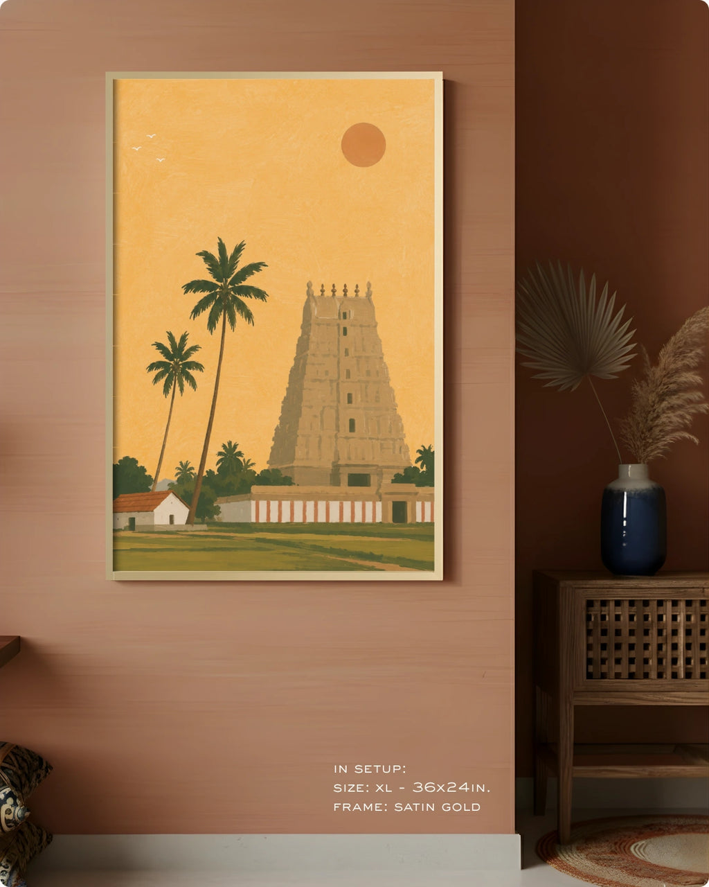 A framed art print depicting a South Asian temple tower and palm trees in warm yellow, green, and beige tones, displayed on a terracotta-colored wall in a styled interior setting.