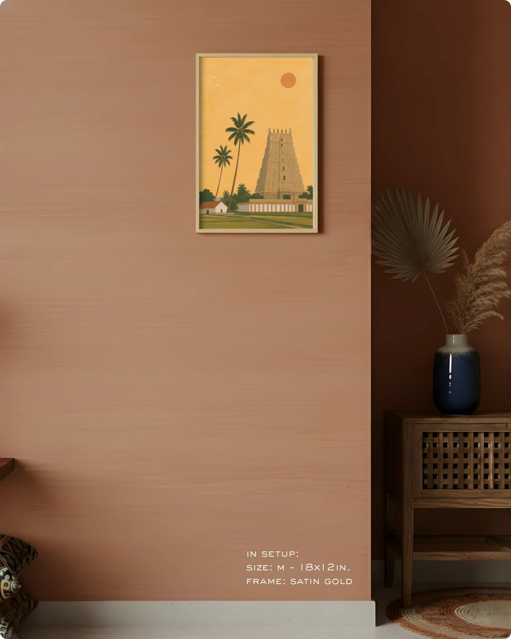 A framed art print depicting a traditional South Indian temple tower and palm trees, styled on a terracotta-colored wall in a modern interior setting.