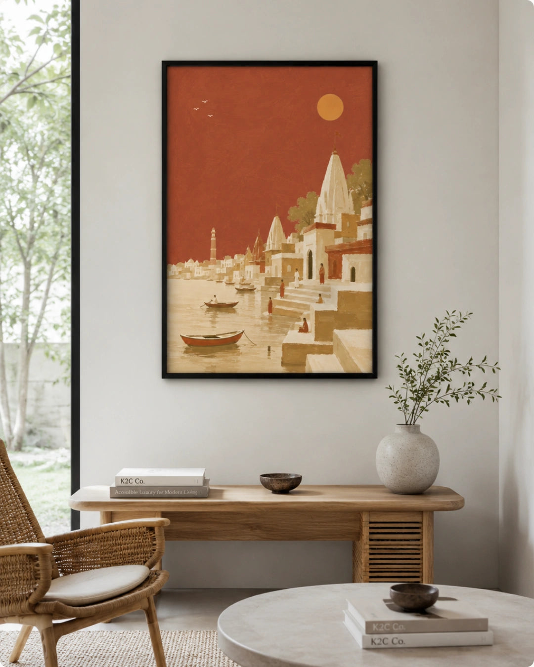 A framed art print depicting a stylized coastal village scene in warm terracotta, beige, and orange tones, displayed on a light gray wall above a wooden console table in a modern living room setting.