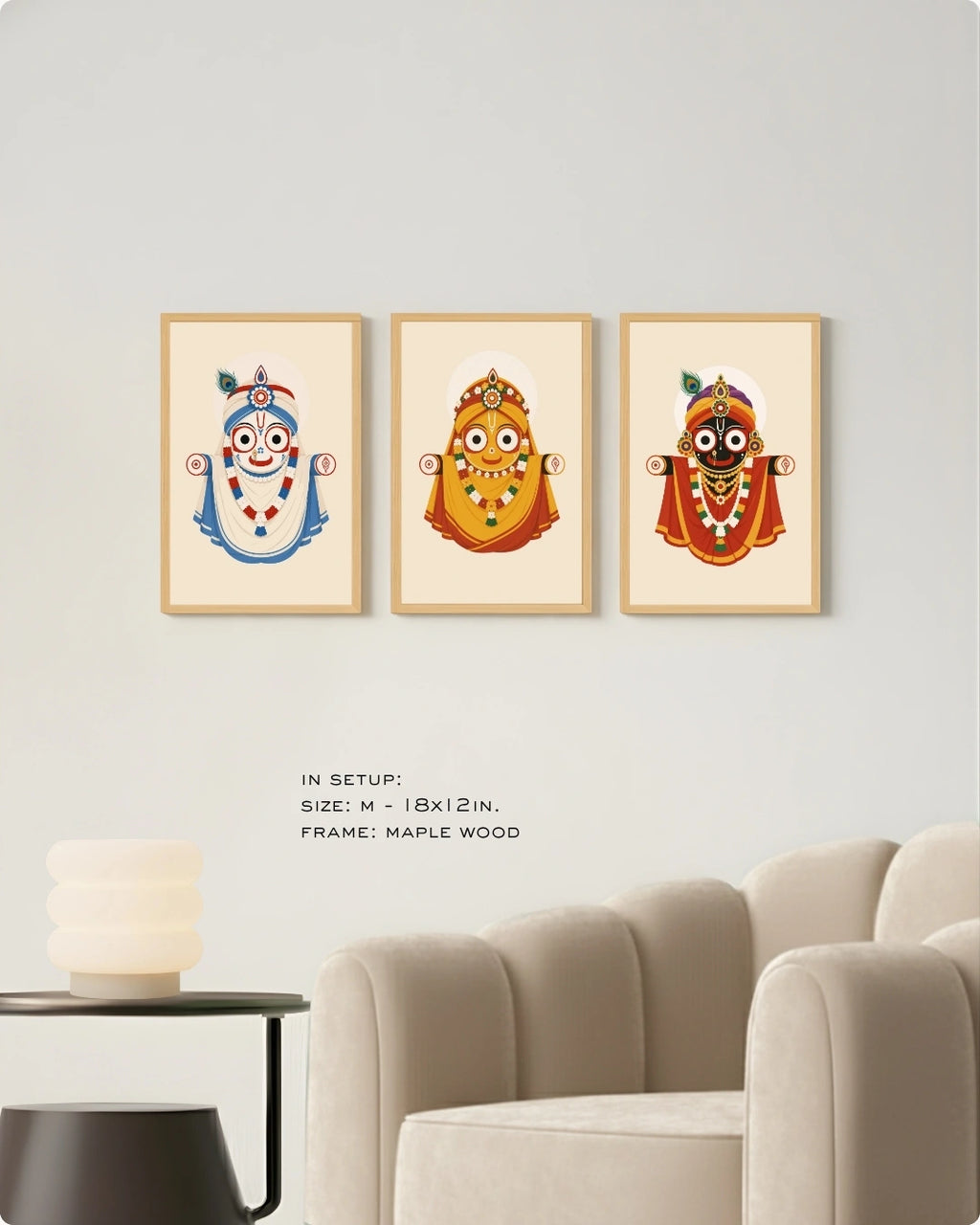 Visual size guide mockup for the Jagannath Triad 3 piece wall art set in Medium size with satin gold frames displayed above a modern ribbed beige armchair.