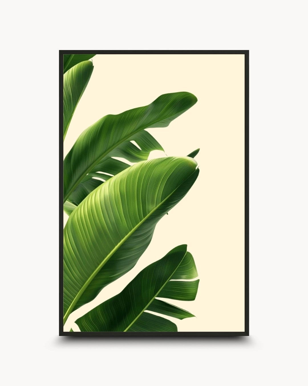 Minimalist botanical leaf artwork by K2C Co. featuring lush green tropical banana leaves on a cream background, set in a Noir Black frame. Ideal for modern Scandinavian living room decor.