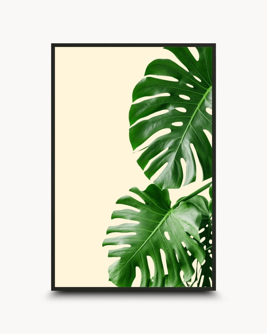 Minimalist botanical Monstera leaf artwork by K2C Co. featuring vibrant green tropical Swiss cheese plant leaves on a cream background, set in a Noir Black frame. Ideal for modern Scandinavian living room decor.