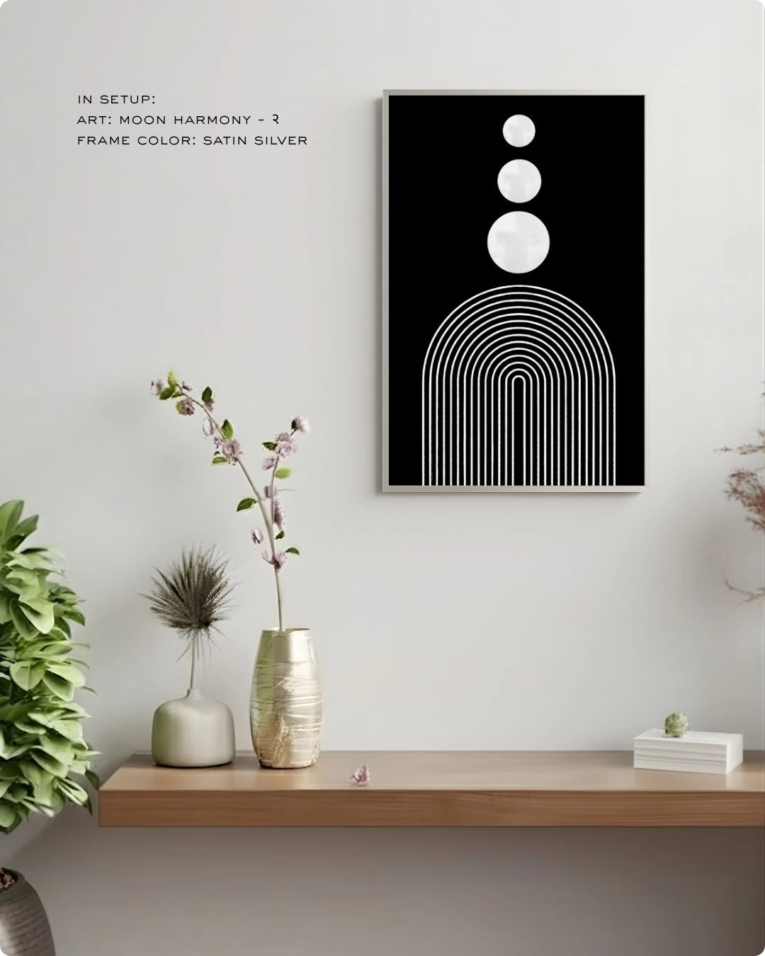 Moon Harmony 2 abstract wall art by K2C Co. featuring three white circles and arches on a solid black background in a Satin Silver frame, displayed in a minimalist living room mockup with floral decor.