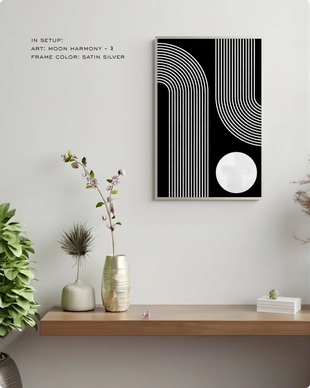 Moon Harmony 3 abstract wall art by K2C Co. featuring a white circle and curved lines on a solid black background in a Satin Silver frame, displayed in a minimalist living room mockup with floral decor.