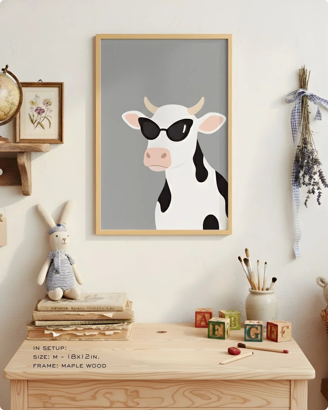 Close-up of the "Cool Cow" illustration in a Maple Wood frame, styled on a child's light wood desk with art supplies.