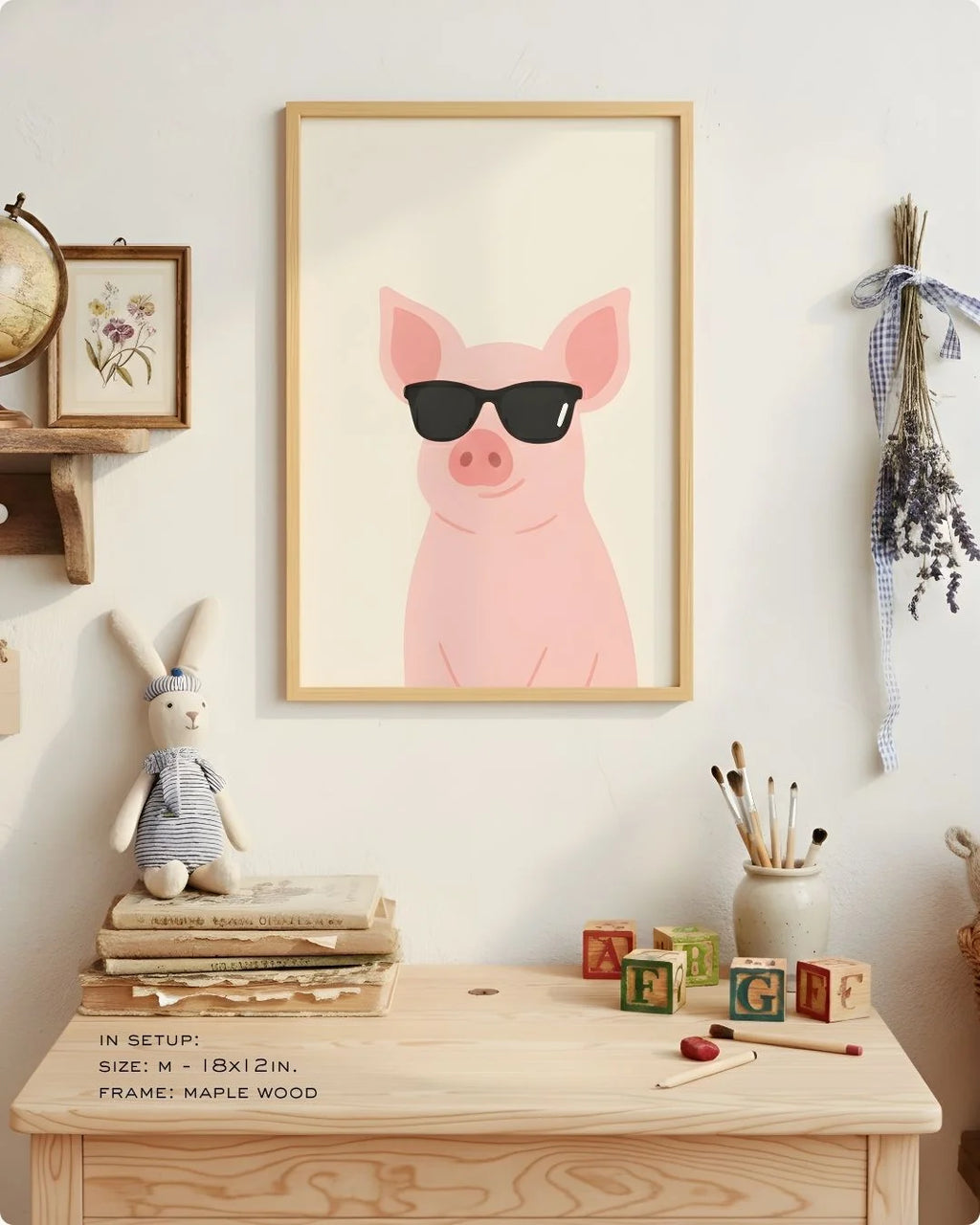 Close-up of the "Cool Pig" illustration in a Maple Wood frame, styled on a child's light wood desk with art supplies and a rabbit plush.