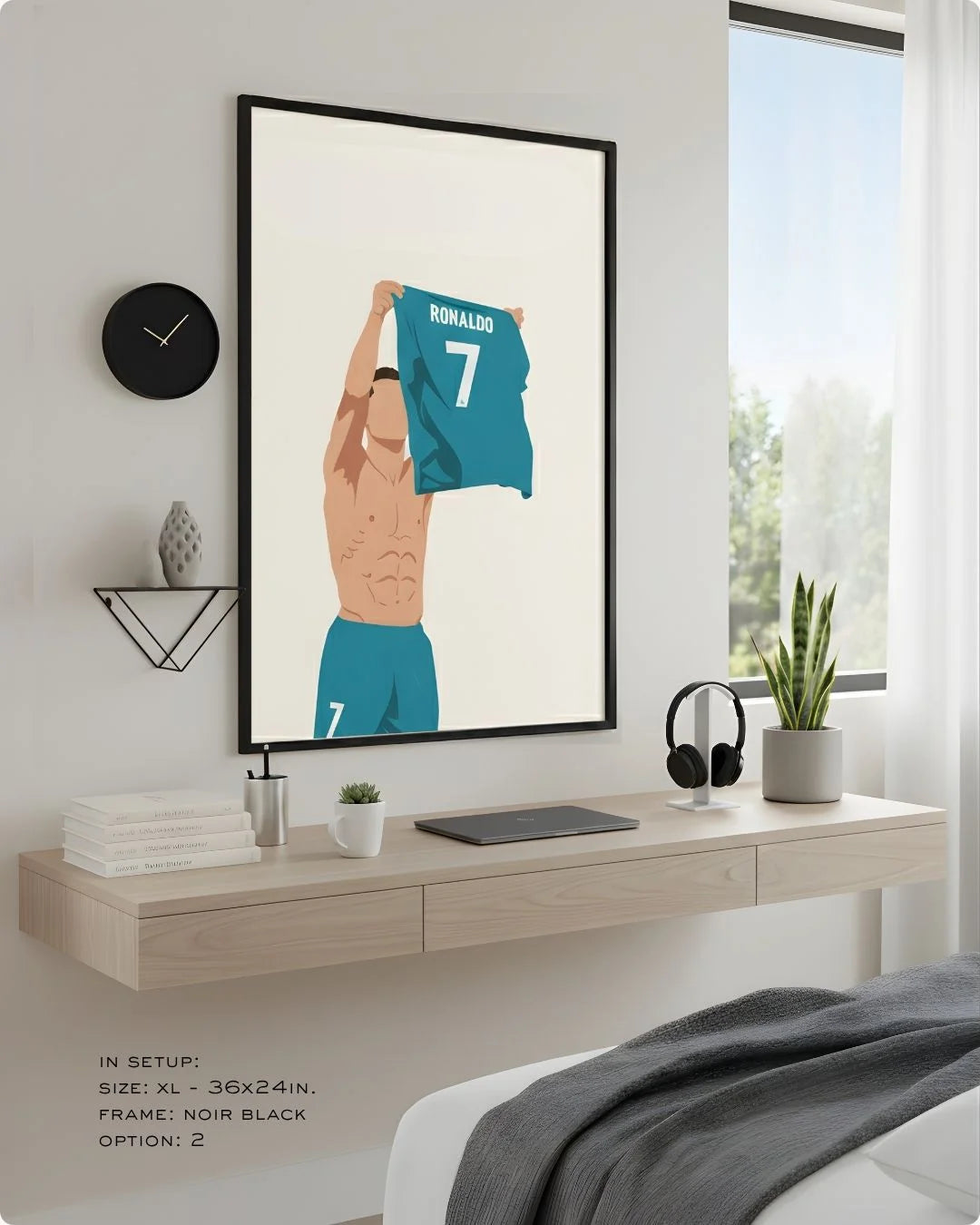 Minimalist Cristiano Ronaldo (CR7) print in an XL Noir Black frame (24x36in) styled above a light wood floating desk in a modern bedroom-office.