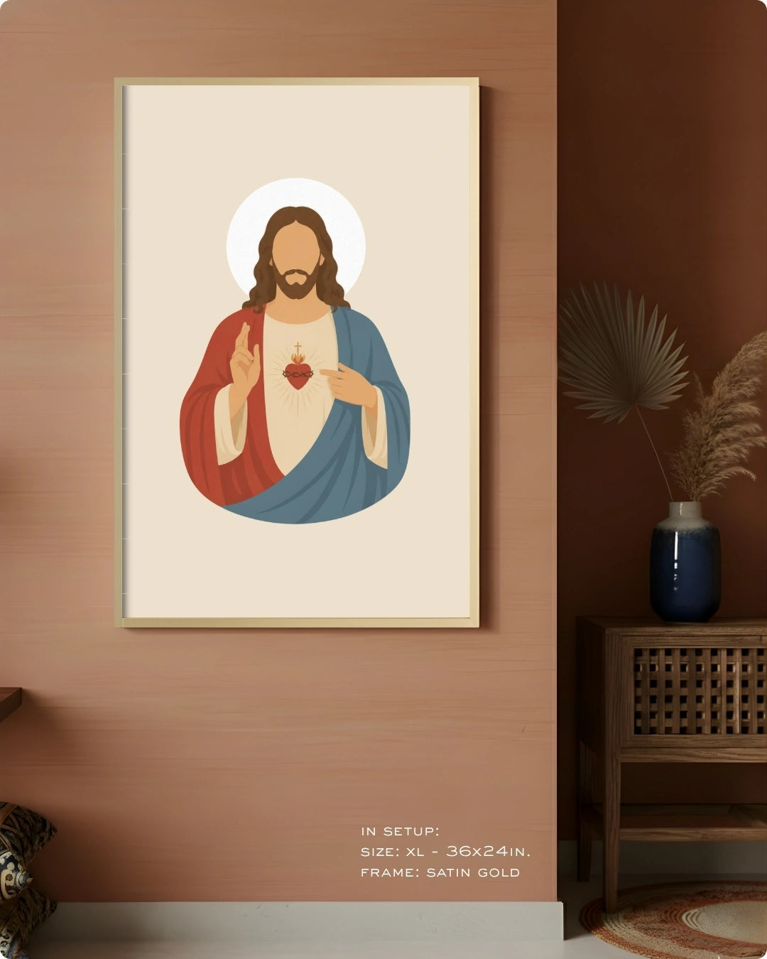 A framed art print of the Sacred Heart of Jesus displayed on a warm terracotta wall in a styled room setting. The print features a minimalist vector illustration of Jesus with a red and blue robe on a cream background, enclosed in a thin gold frame.