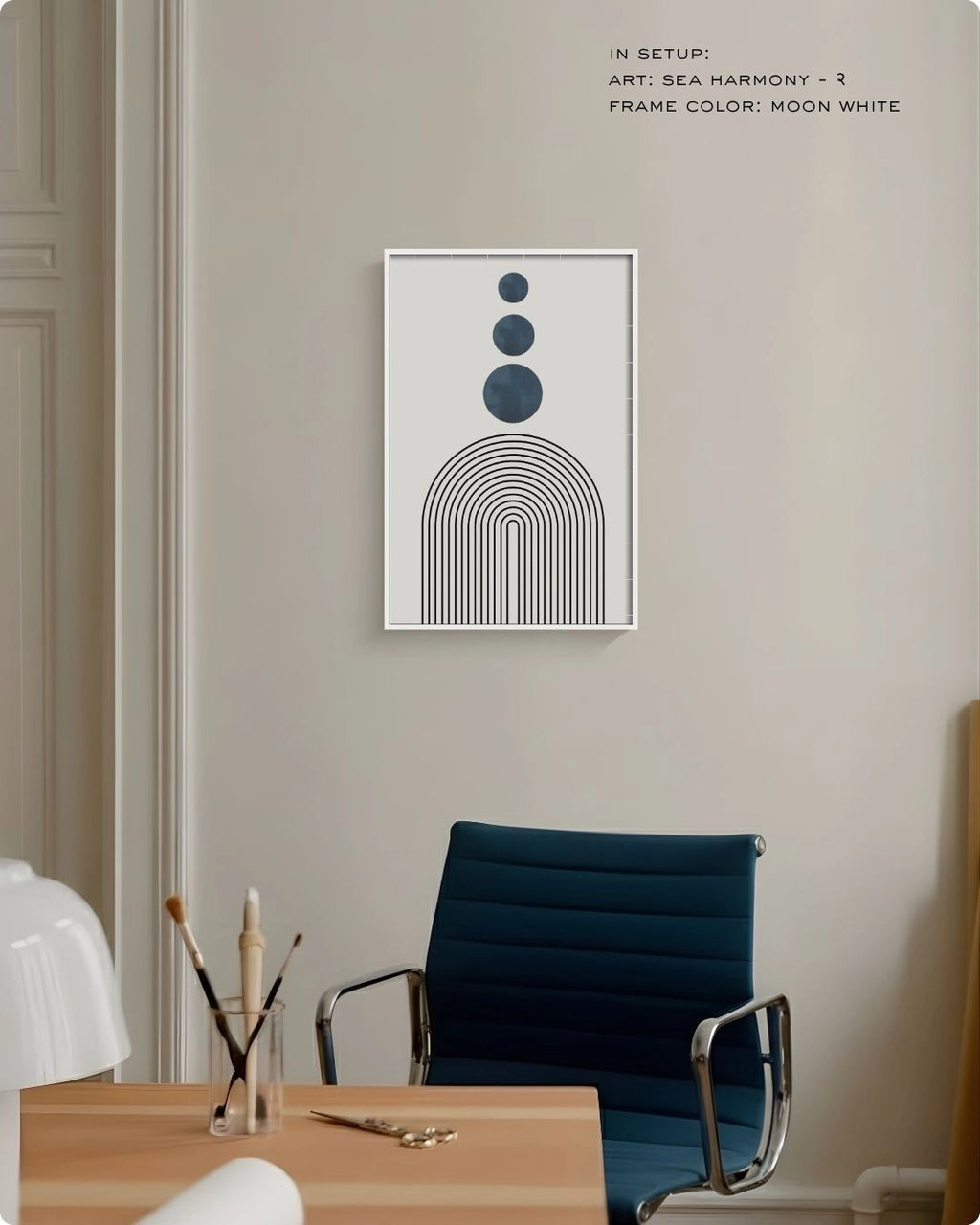 Sea Harmony 2 abstract wall art by K2C Co. featuring three deep blue circles and black arches in a Moon White frame, displayed in a minimalist office setting with a blue desk chair.