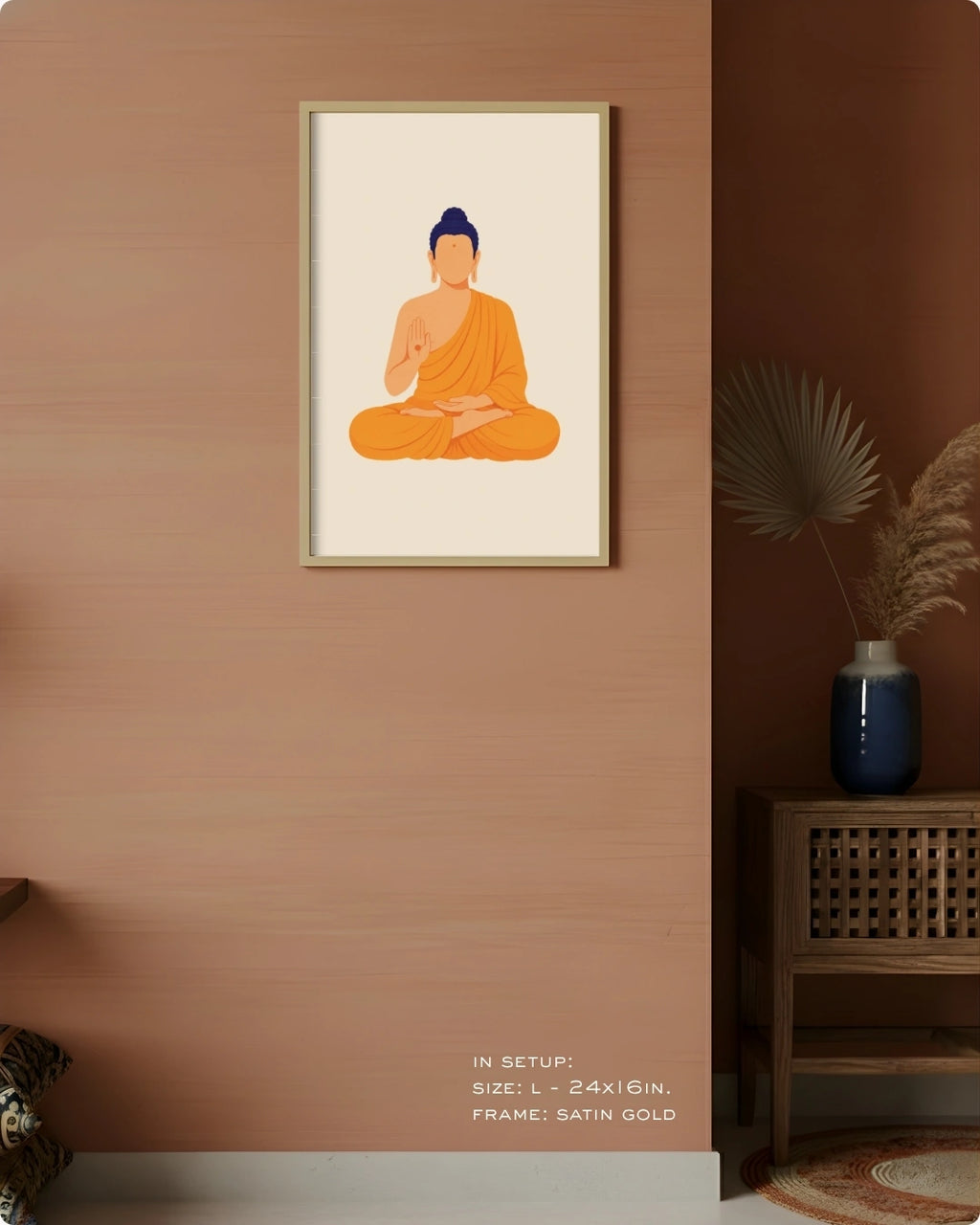 A framed minimalist art print of a meditating Buddha in orange robes, displayed on a warm brown wall in a styled interior setting with a wooden side table and vase.
