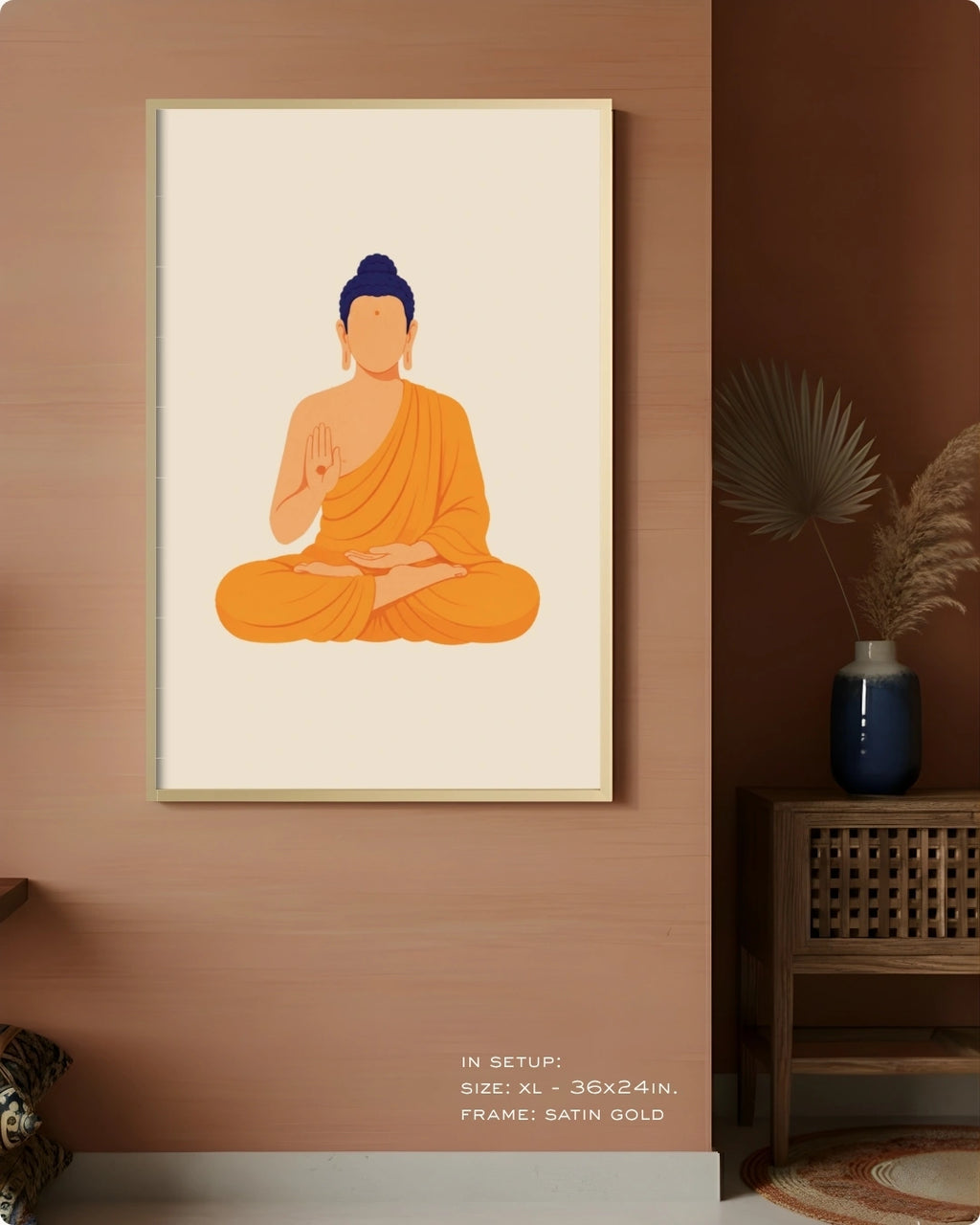 A framed minimalist art print of a seated Buddha in orange robes with a blue head, displayed on a warm brown wall in a styled interior setting with a side table and vase.