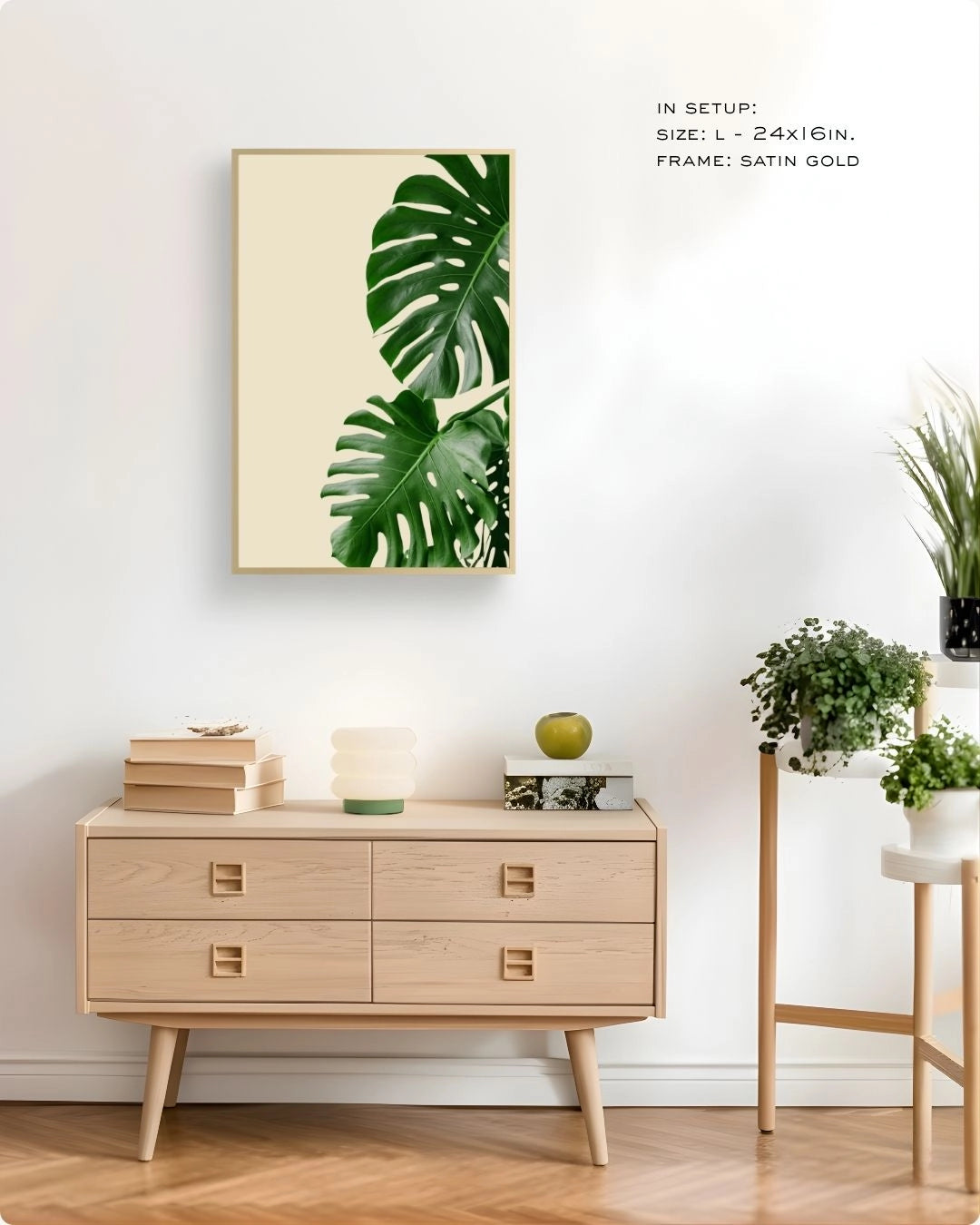 K2C Co. tropical banana leaf print in a Maple Wood frame, styled in a minimalist home office or living room with a light wood chest of drawers and stacks of books.