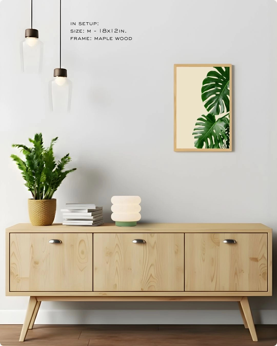Medium-sized tropical botanical print by K2C Co. in a Maple Wood frame, displayed in a modern living room setting on a light wood sideboard with natural decor accents.