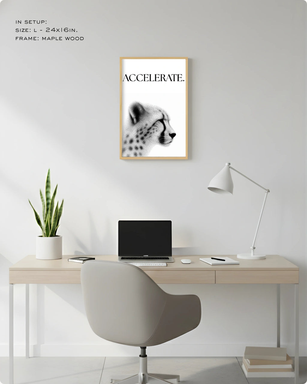 A framed black and white cheetah poster with the word 'ACCELERATE.' hanging on a white wall above a light wood desk setup with a chair, lamp, laptop, and plant.