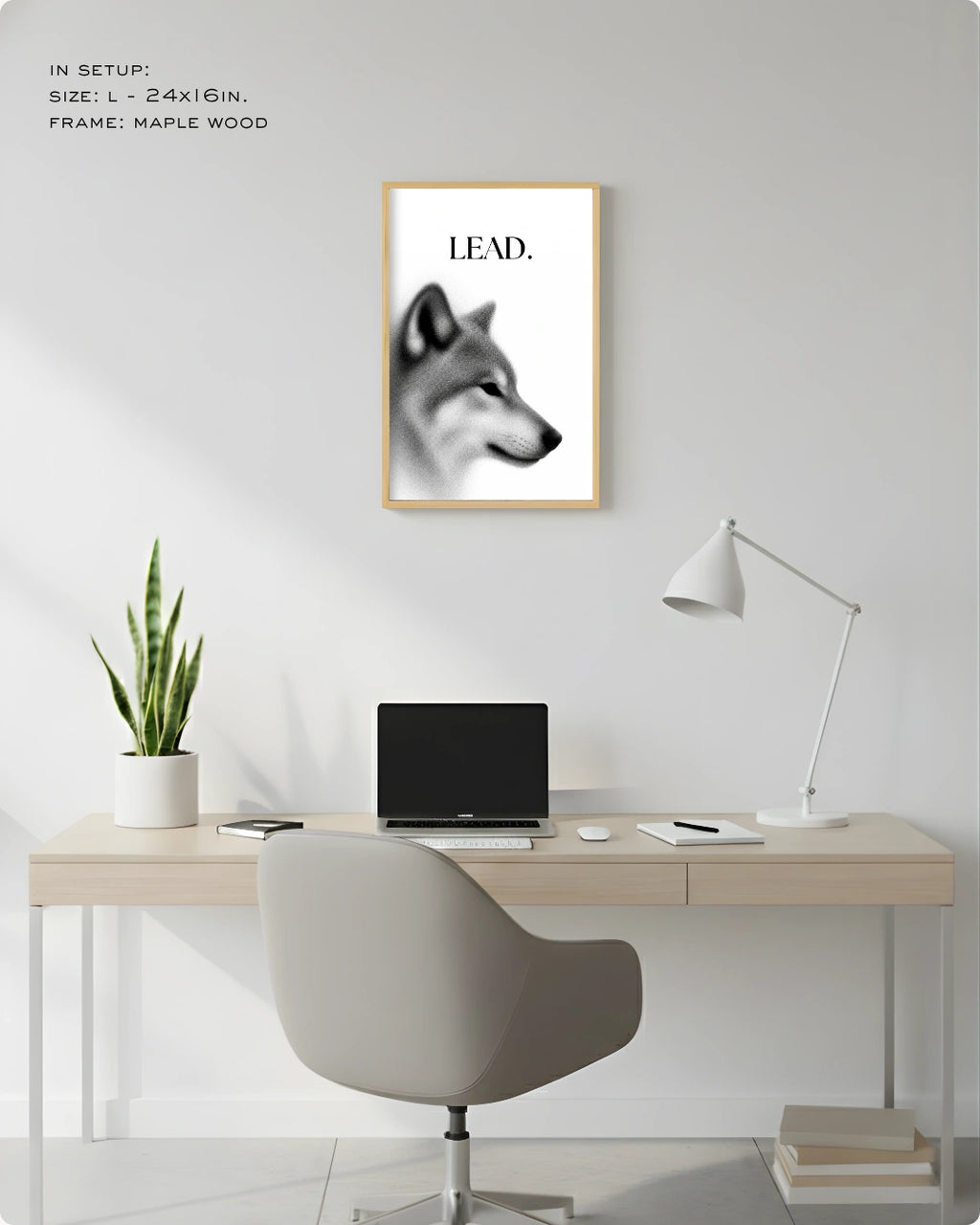 A framed wall art print featuring a black-and-white wolf head with the word “LEAD.” above a minimalist desk setup in a bright home office.