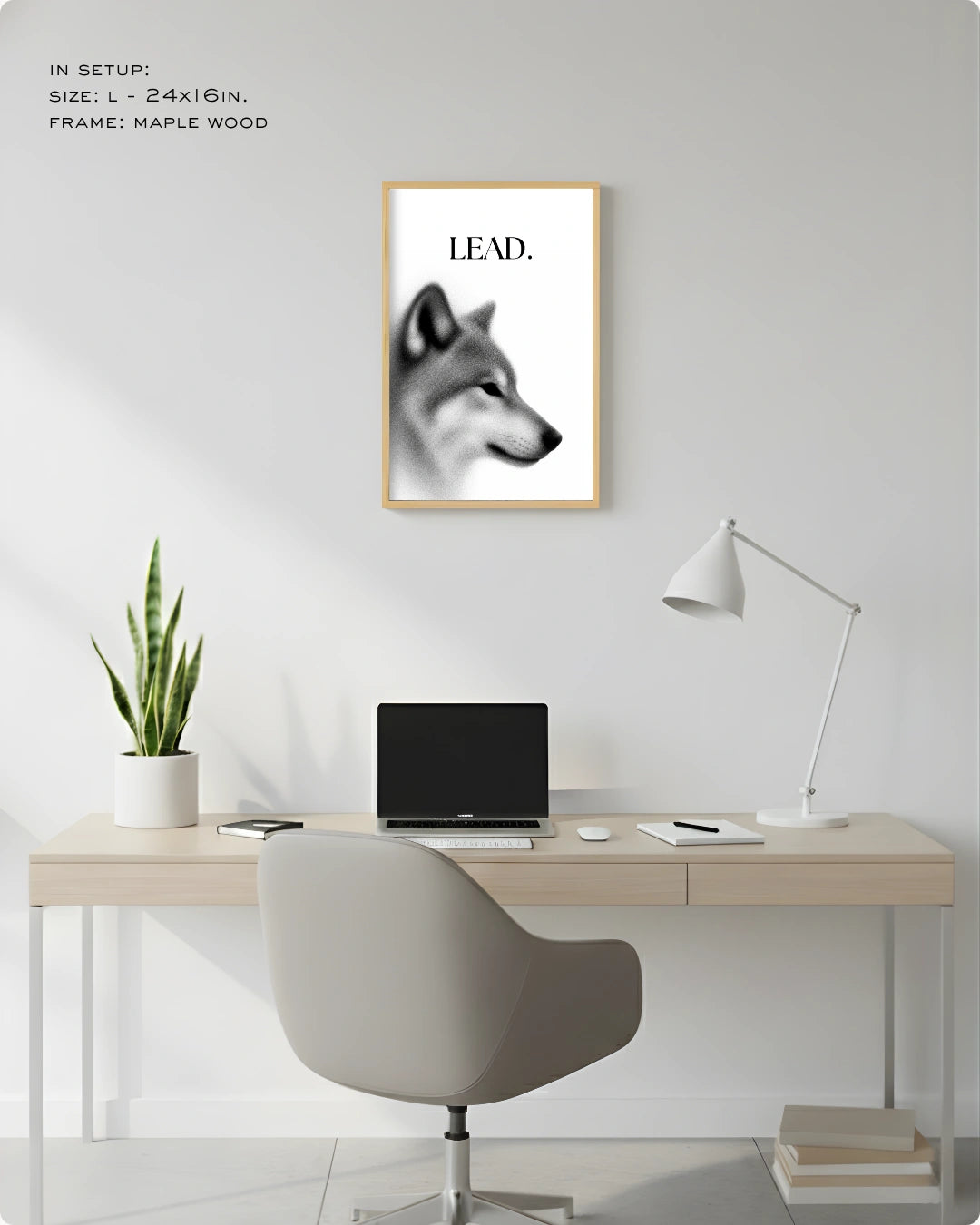 A framed wall art print featuring a black-and-white wolf head with the word “LEAD.” above a minimalist desk setup in a bright home office.